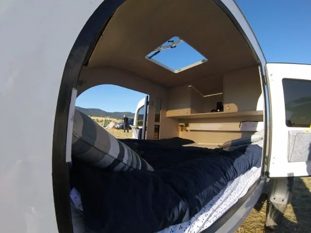 The interior includes a queen-size bed, shelves and cabinets
