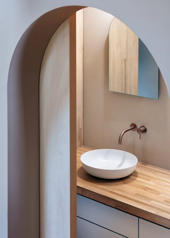 Compact bathroom is hidden behind an arched sliding door