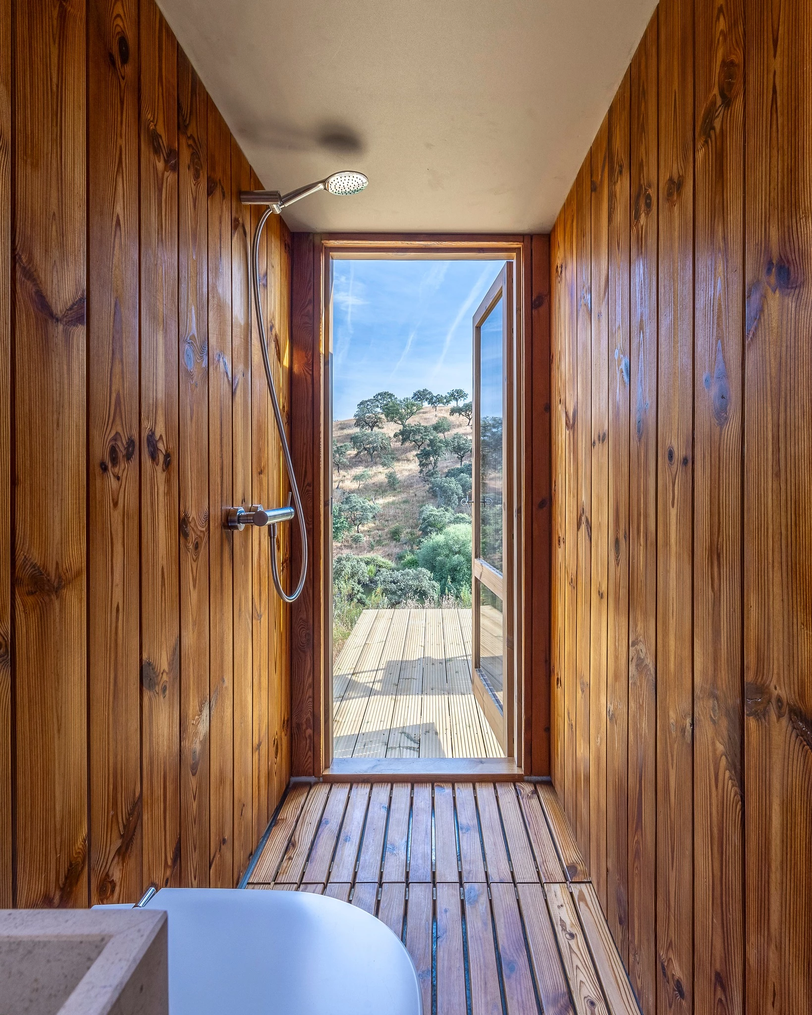 The Terra m3_Tiny House's bathroom includes a shower, sink, and toilet, and offers direct access to its terrace area outside