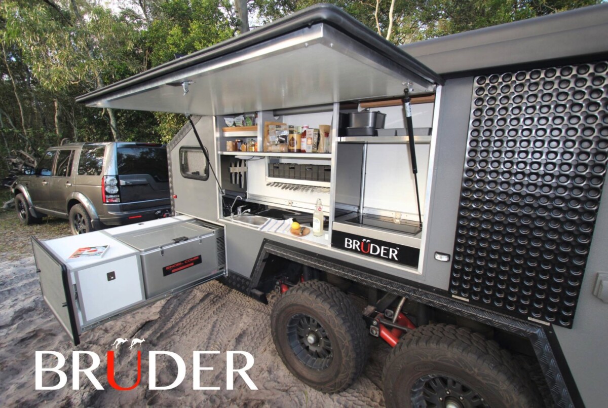 The design includes an indoor/outdoor cooktop and a slide-out fridge/freezer