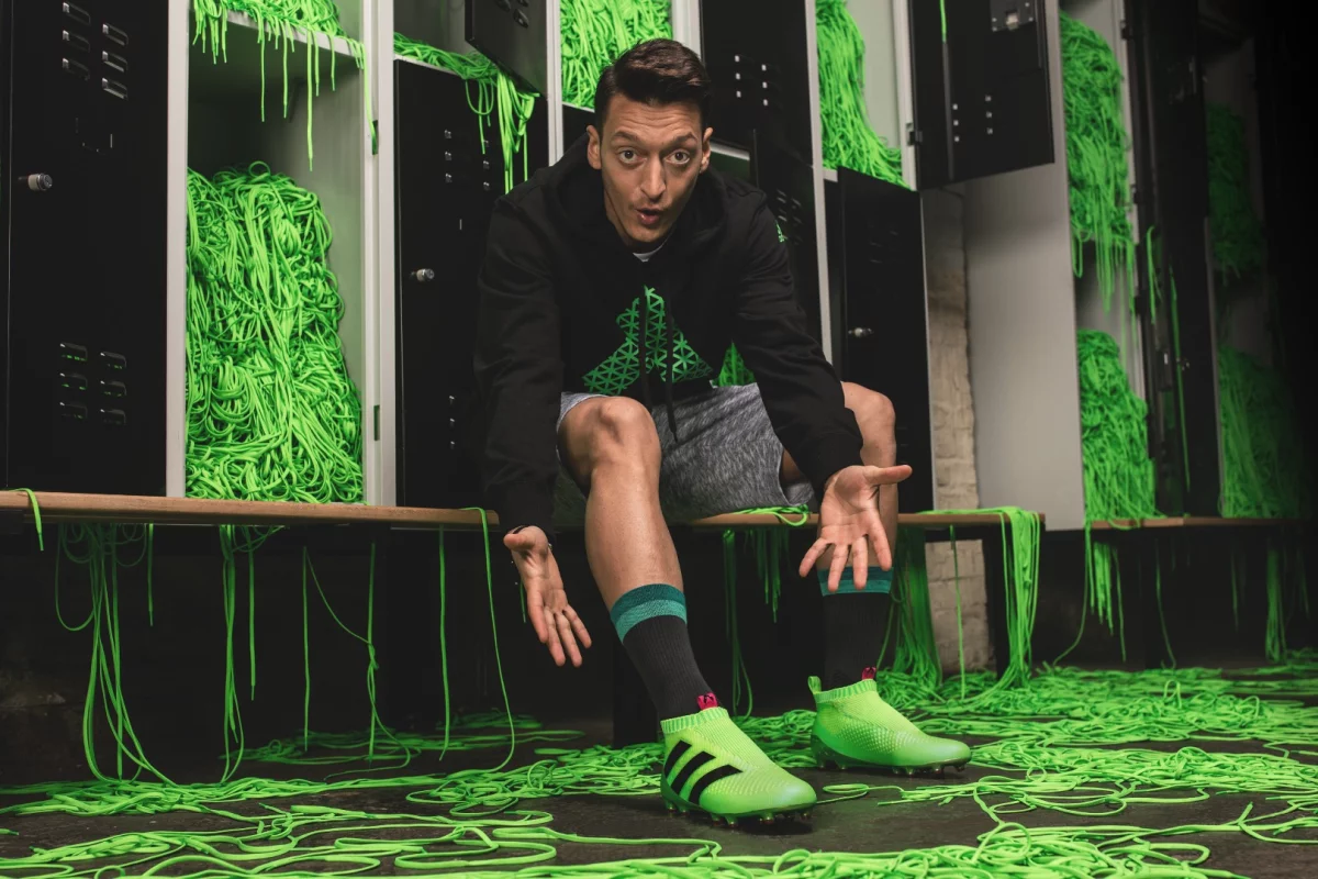 Arsenal's Mesut Ozil tries on a pair of Adidas' laceless football boots