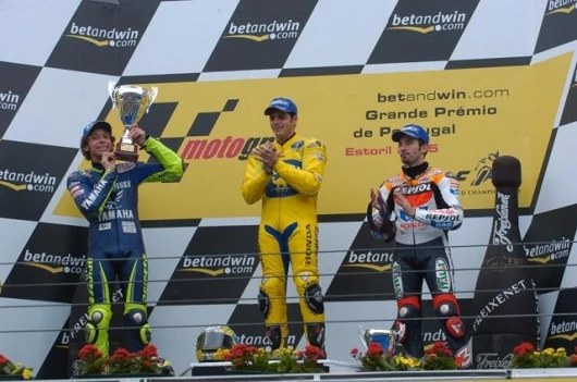 Rossi lifts the second place trophy. to the applause of Barros and Biaggi