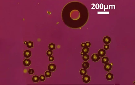 A bubble microrobot, visible in the top center, arranged tiny glass beads to form the HU acronym