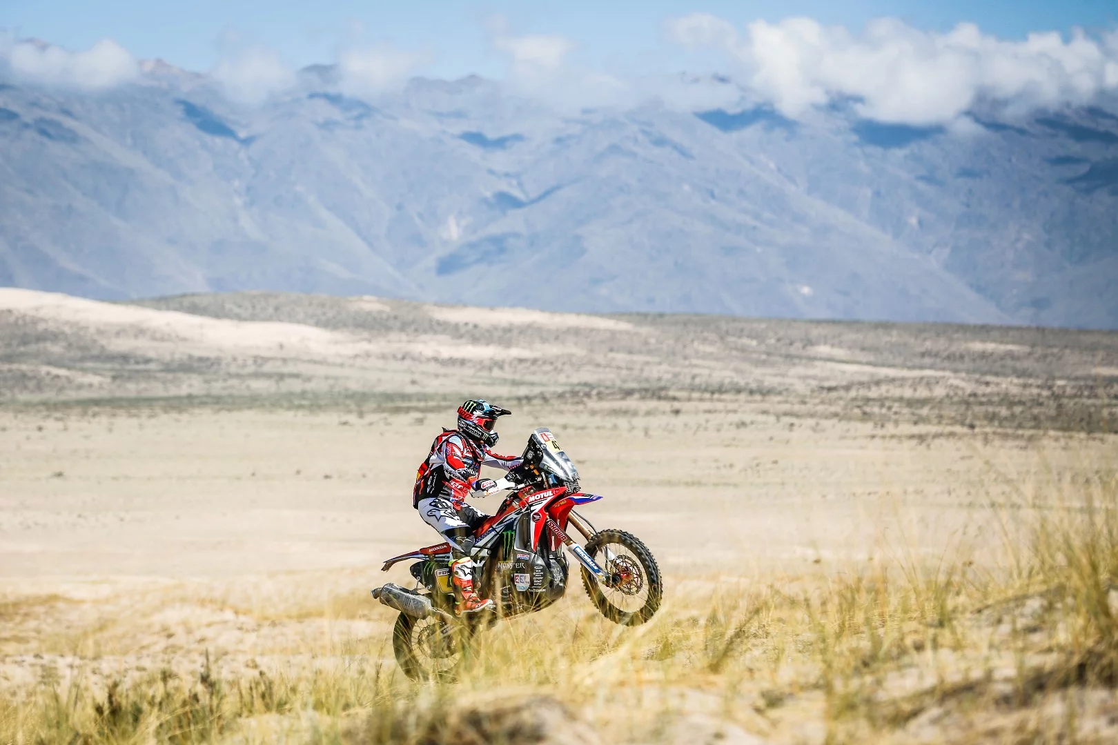 Argentinian Honda rider Kevin Benavides wheelies through his home turf in stage 10, with the magnificent Andes providing the backdrop