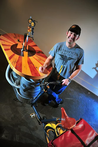 The Beer Bike is a custom-built cargo bicycle that features two beer kegs, a wooden bar with two serving taps, space for pizza boxes, and a solar-powered boom box