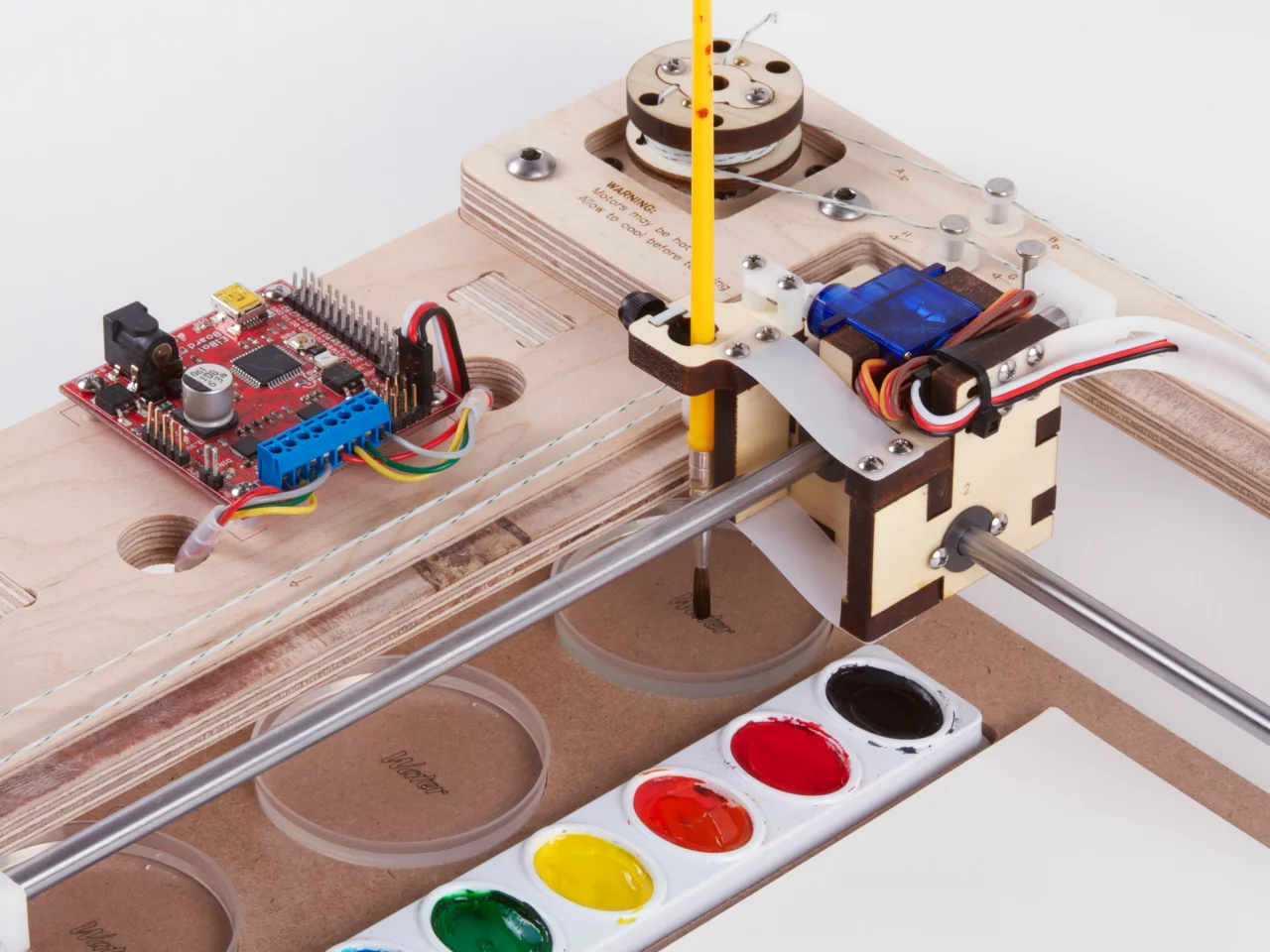 The mechanism works much like other drawing machines that are on the market, except for the addition of three dishes of water that clean the brush between colors