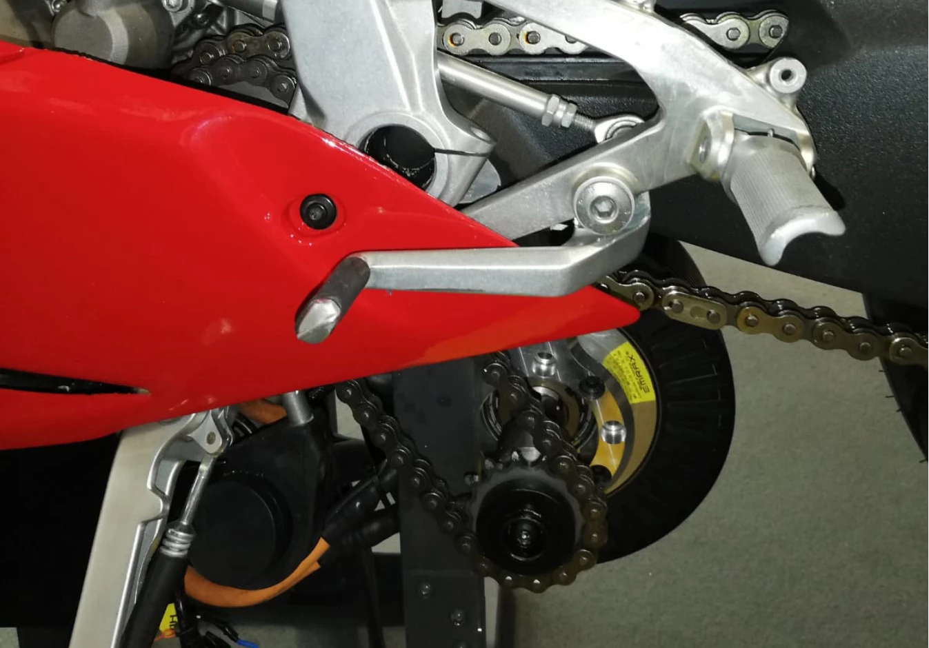 A sprocket on the electric motor's output shaft drives a chain leading to a second sprocket on the engine output shaft