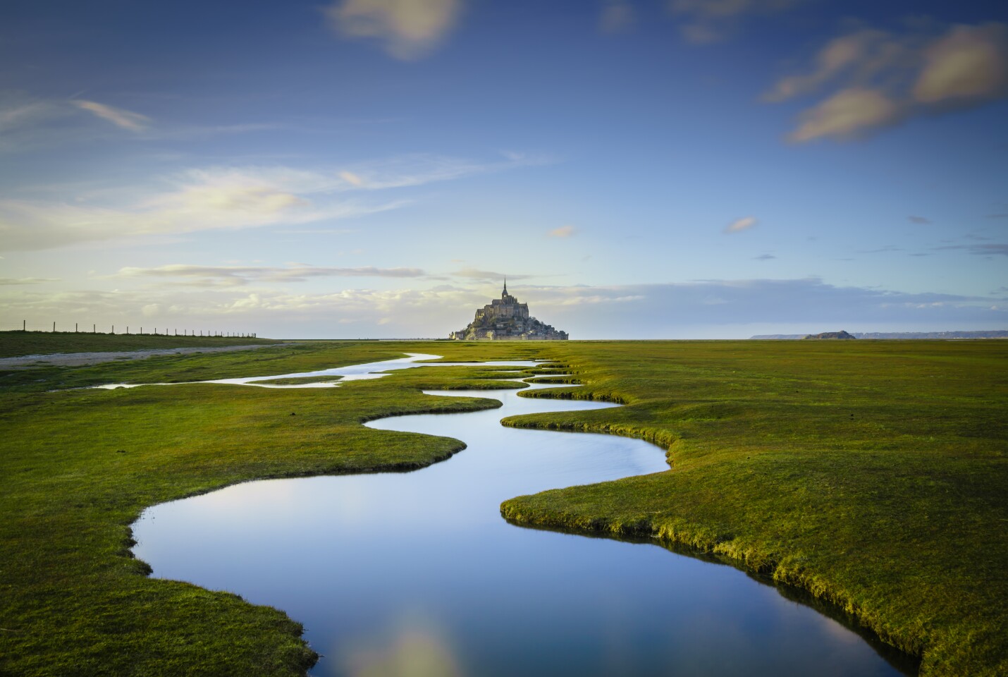 Overall Winner - Mont Saint-Michel. "Les Méandres: The medieval island commune of Le Mont Saint-Michel sits off the northwestern coast near the border between Brittany and Normandy in France. This photograph, taken during the spring tide in early March 2018, shows the curious land formations known locally as Les Méandres. The channels fill up in late afternoon and reflect the setting sun to create a mirror pool effect."