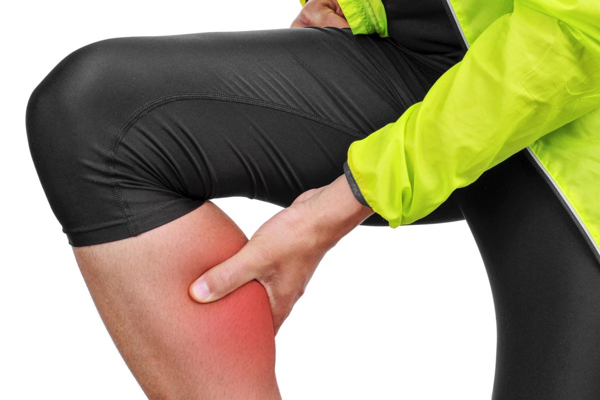 closeup of a young caucasian sportsman wearing sport clothes with his hand in his calf because of his calf muscle pain
