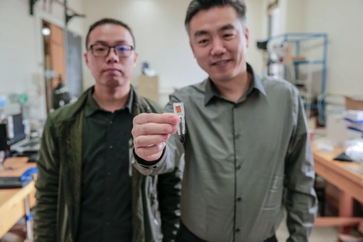 Graduate student Guang Yao (left) and Xudong Wang (right) hold a small implantable device that helped rats lose 40 percent of their body weight