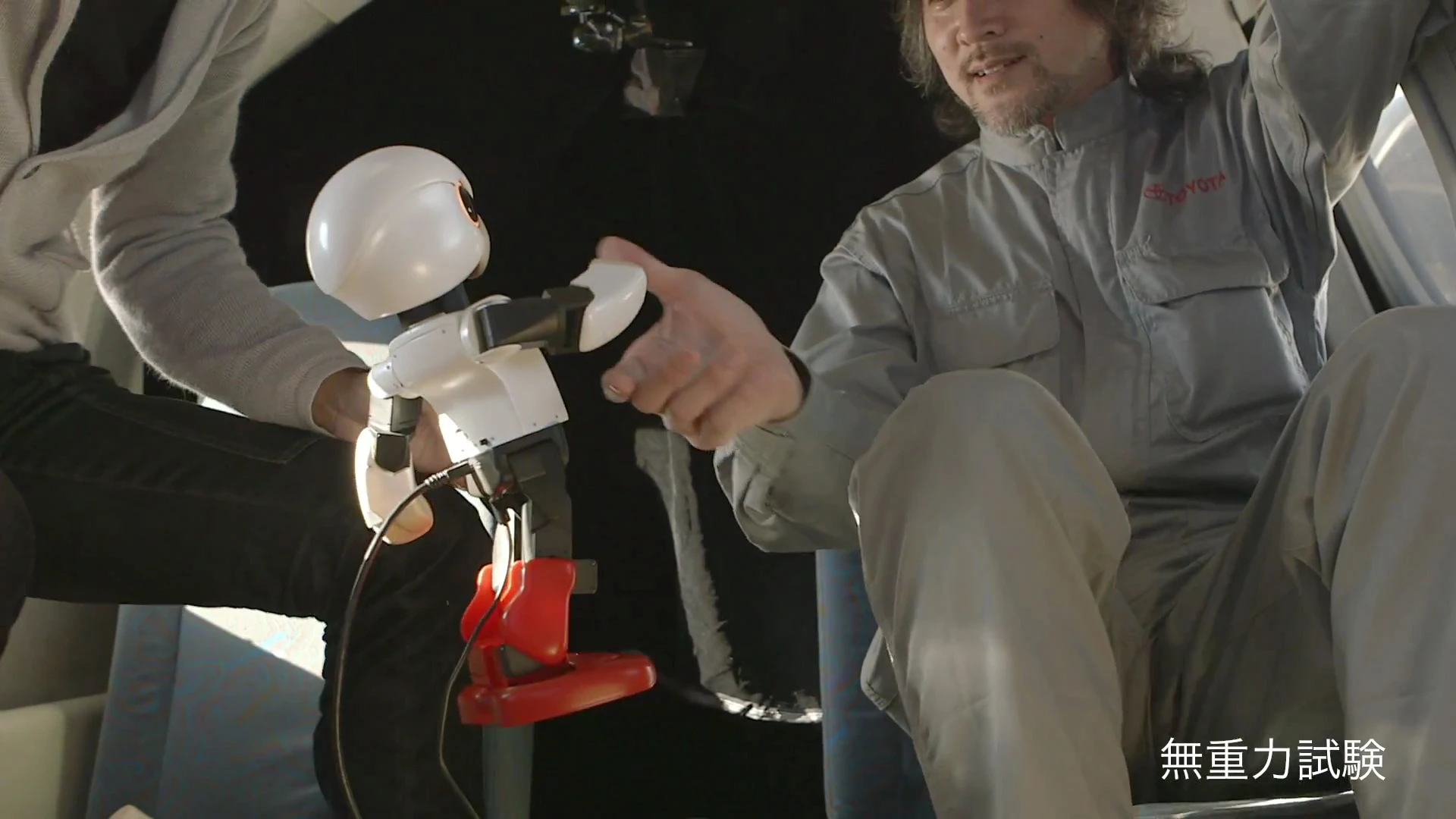 Kibo shakes hands with one of Toyota's designers in zero gravity