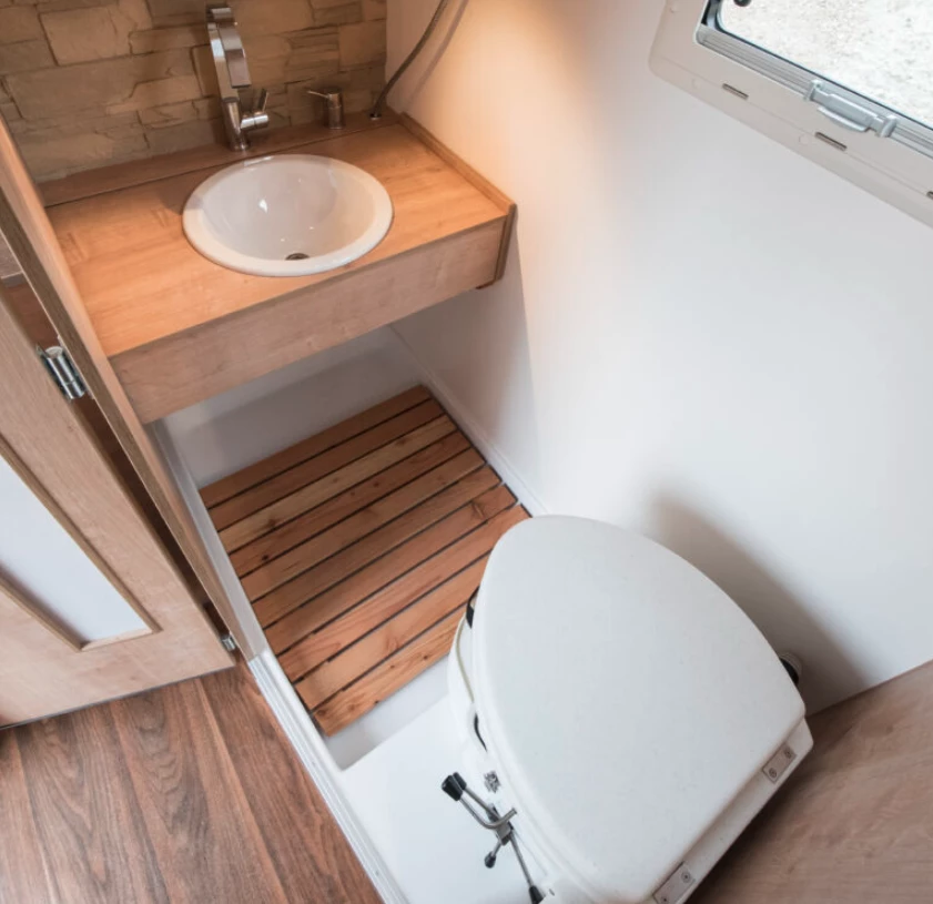 The sink slides out from behind the bathroom wall in the upper left corner of the photo, disappearing away for full shower access