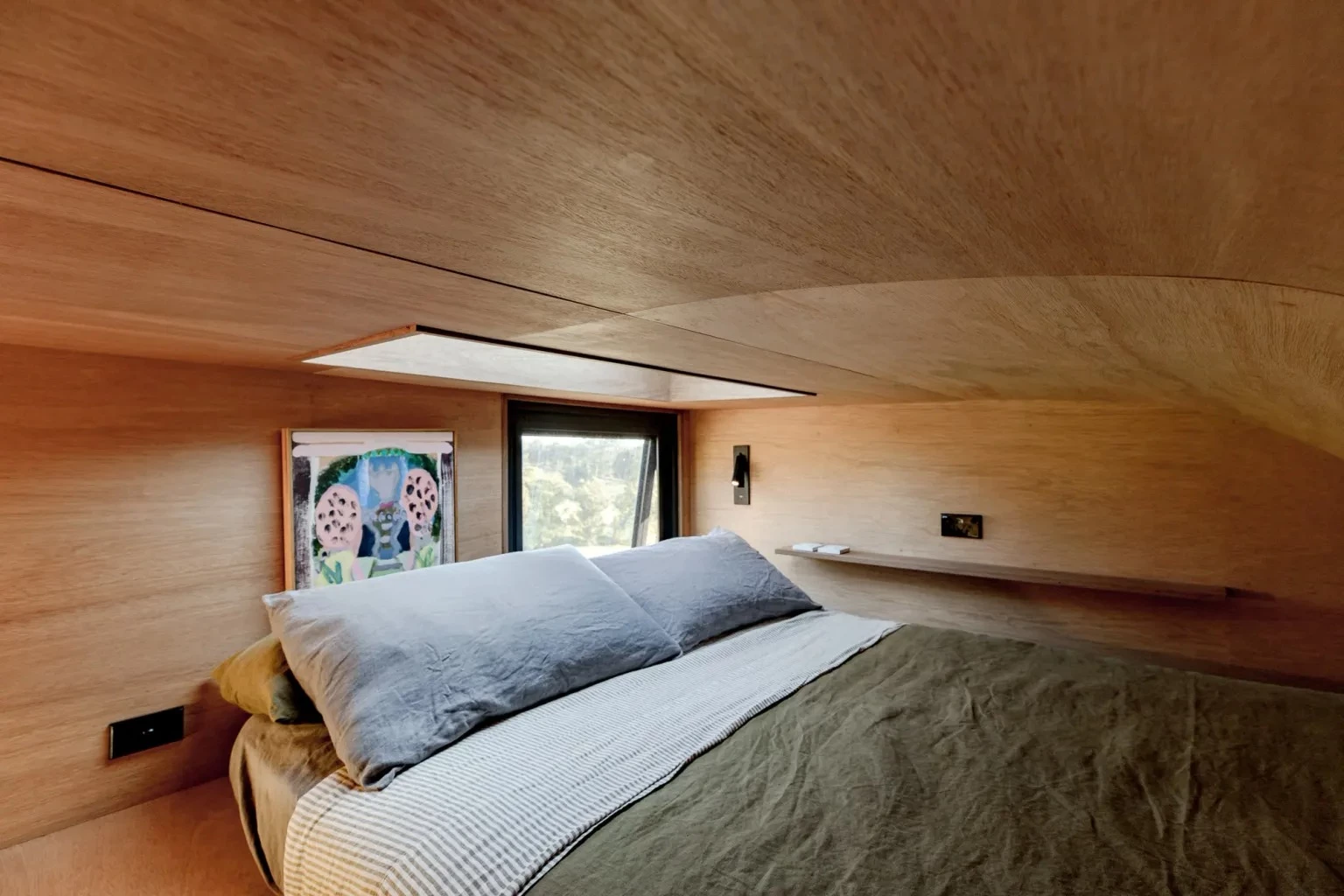 The Fowler & Ward x Base Cabin's upstairs bedroom is a typical loft room with a low ceiling and a double bed. It also includes a skylight for stargazing
