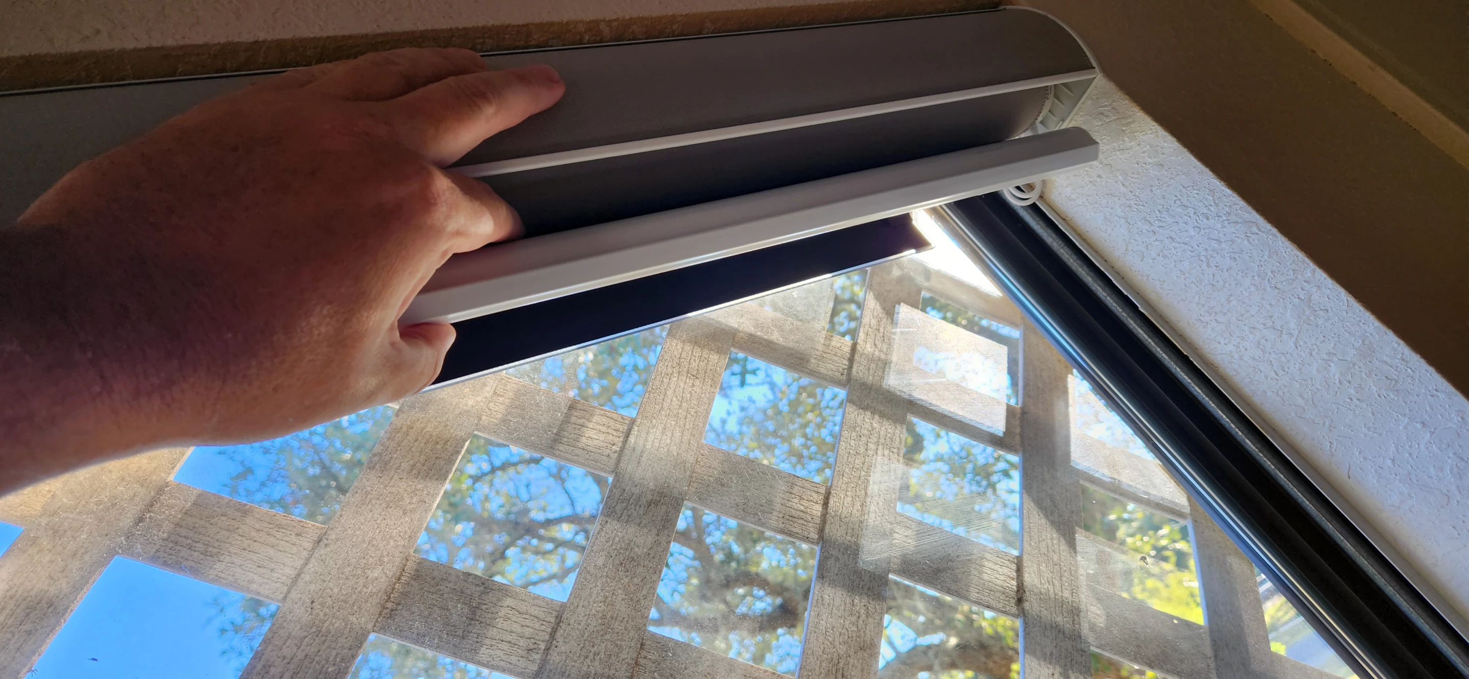 Taking a peek under the shade after I installed it, you can just see the little solar panel stuck to the window that keeps the batteries topped up so I never have to think about it