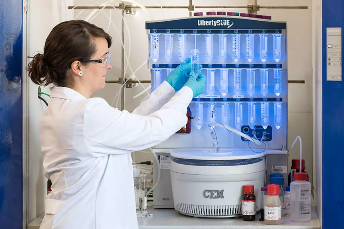 Project researcher Marta Tena-Solsona, with the peptide synthesizer that produces the molecular building blocks of the self-destructing materials