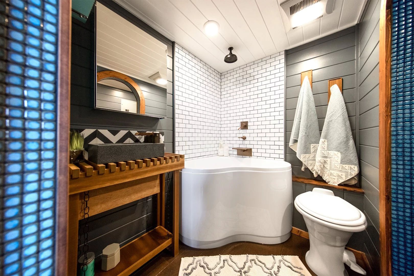 The Tiny Adventure Home's bathroom includes a corner soaking tub/shower unit