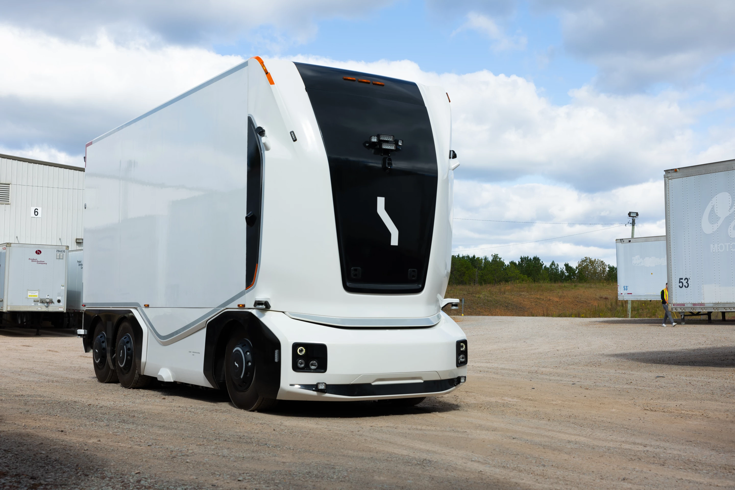 The cabless autonomous electric truck hauls goods between a manufacturing facility and warehouse, with docking and loading/unloading also undertaken autonomously
