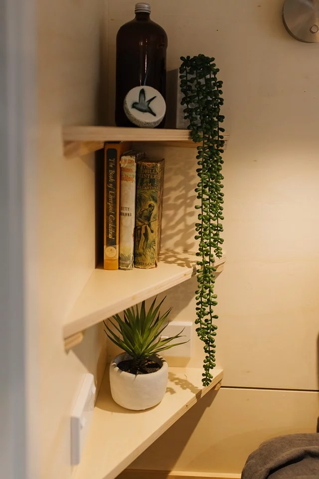The Green Hill Farm Tiny House's bathroom includes some shelving and storage space