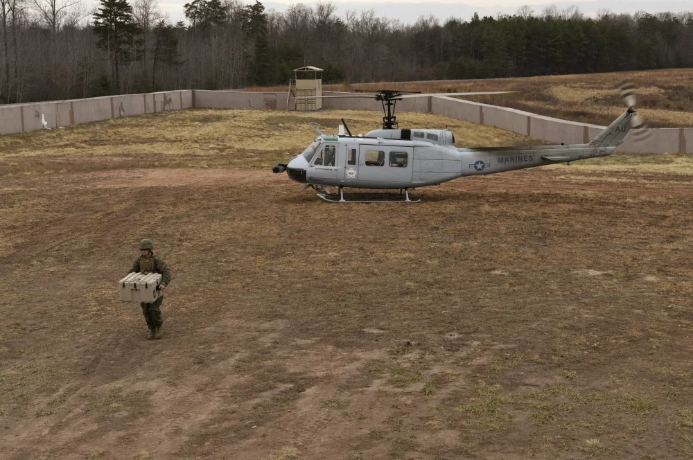 A Marine offloads cargo from a UH-1 Huey equipped with an AACUS autonomy kit