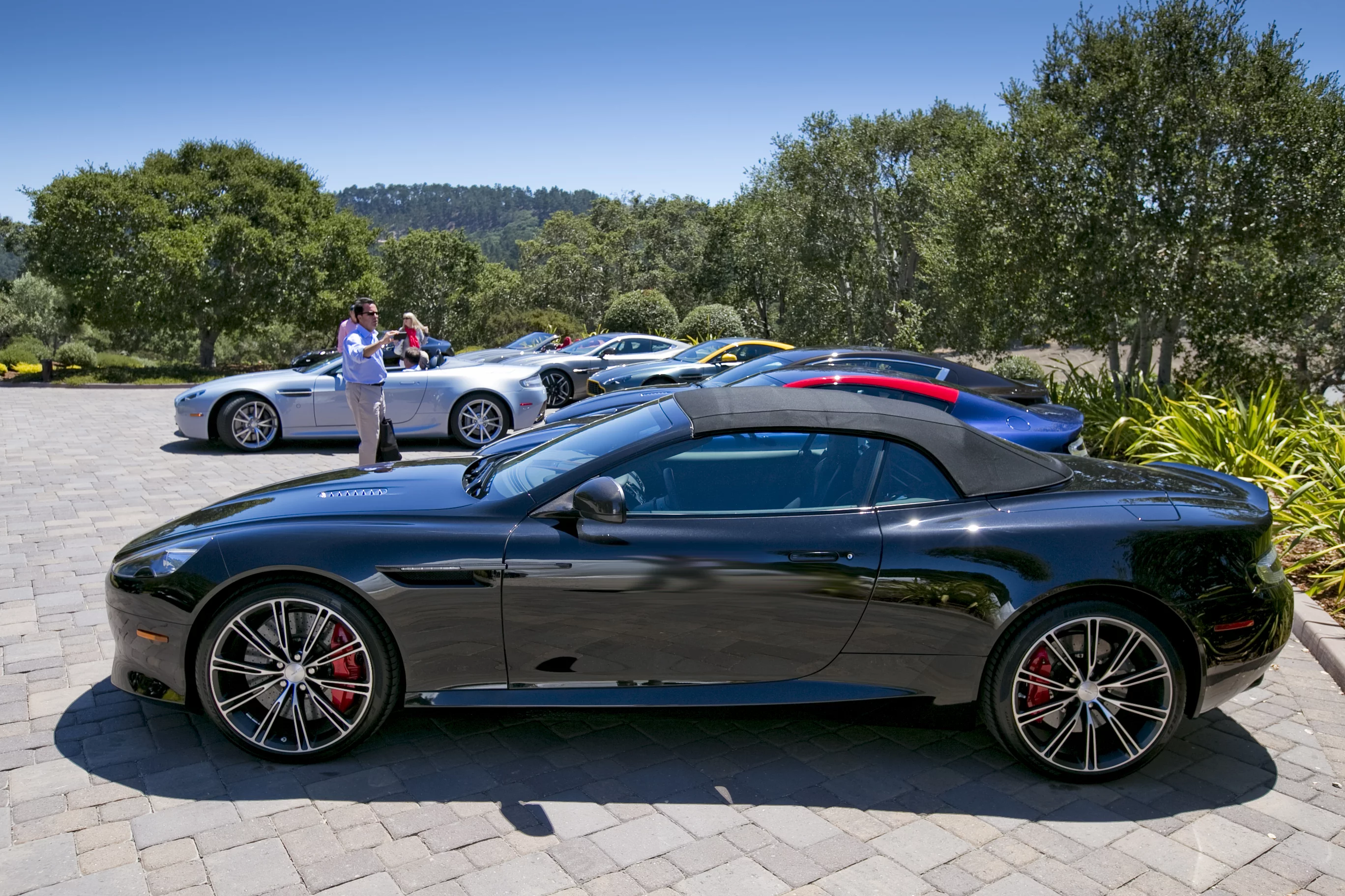 A dozen or so Aston Martins greet guests in the dusty, hot hills outside of Monterey earlier this month (Photo: Angus MacKenzie/Gizmag.com)