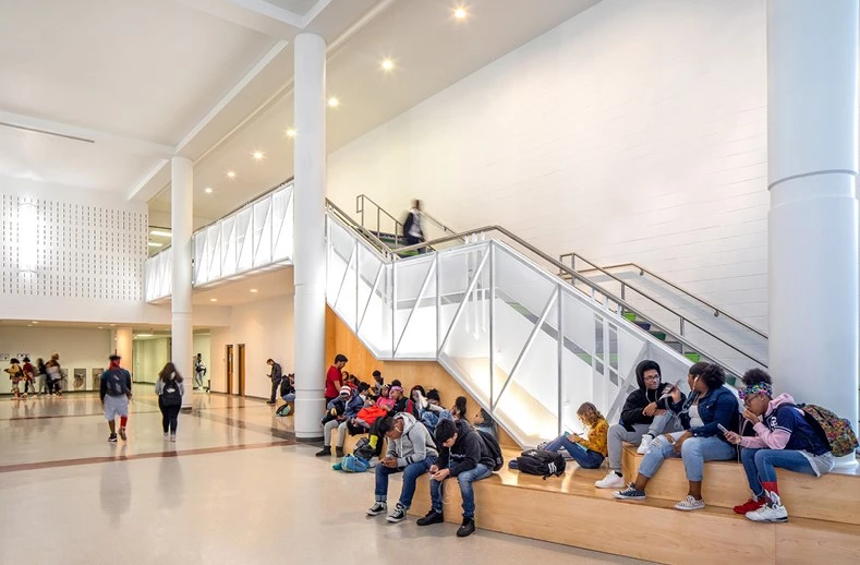 The Southeast Raleigh Magnet High School Great Hall Renovation enhanced a dull and poorly lit high school entry hall, adding extra seating and lighting
