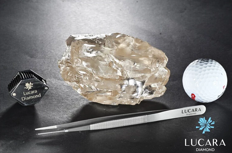 The Lucara diamond with a golf ball, tweezers, and a magnifying loupe for scale