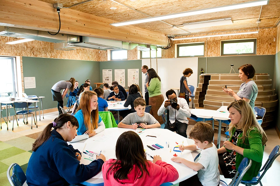 Inside, the classroom looks almost unfinished. The chipboard walls are visible, as are all the ducts, cables, conduits and structural supports, allowing the children to see firsthand how the building works
