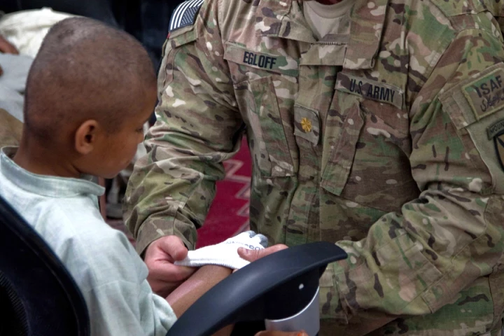 Maj. Brian Egloff puts a sock on an 8-year-old Afghan boy to aid the fitting of the prototype prosthetic leg (Image: Pfc. Justin Young)