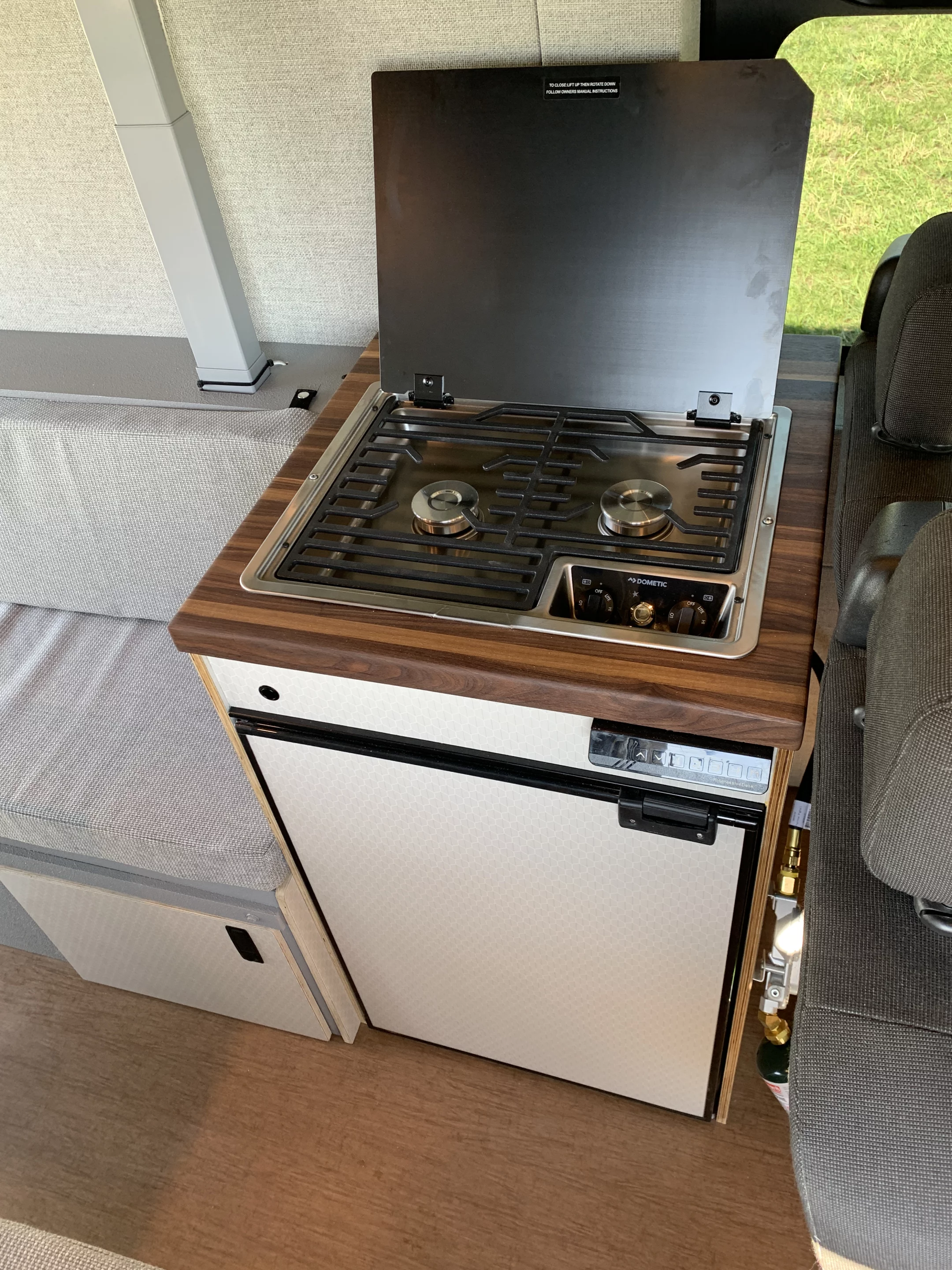 The available Dometic dual-burner stove sits atop the DC fridg e