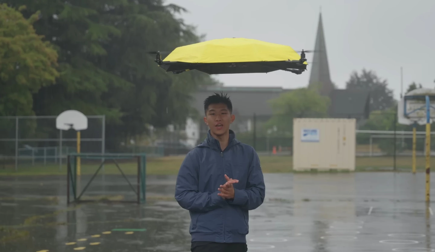 YouTuber John Xu beneath his autonomous flying umbrella, which hovers above him and shelters him from rain