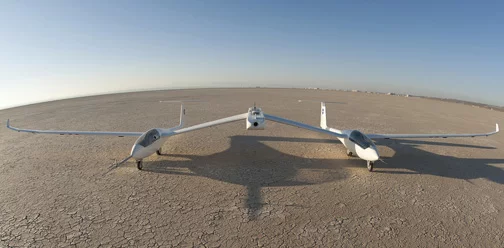 The one-third-scale twin fuselage towed glider rests of the cracked bed of Rogers Dry Lake at Edwards Air Force Base prior to its first flight Oct. 21, 2014 (Photo: NASA / Tom Tschida)