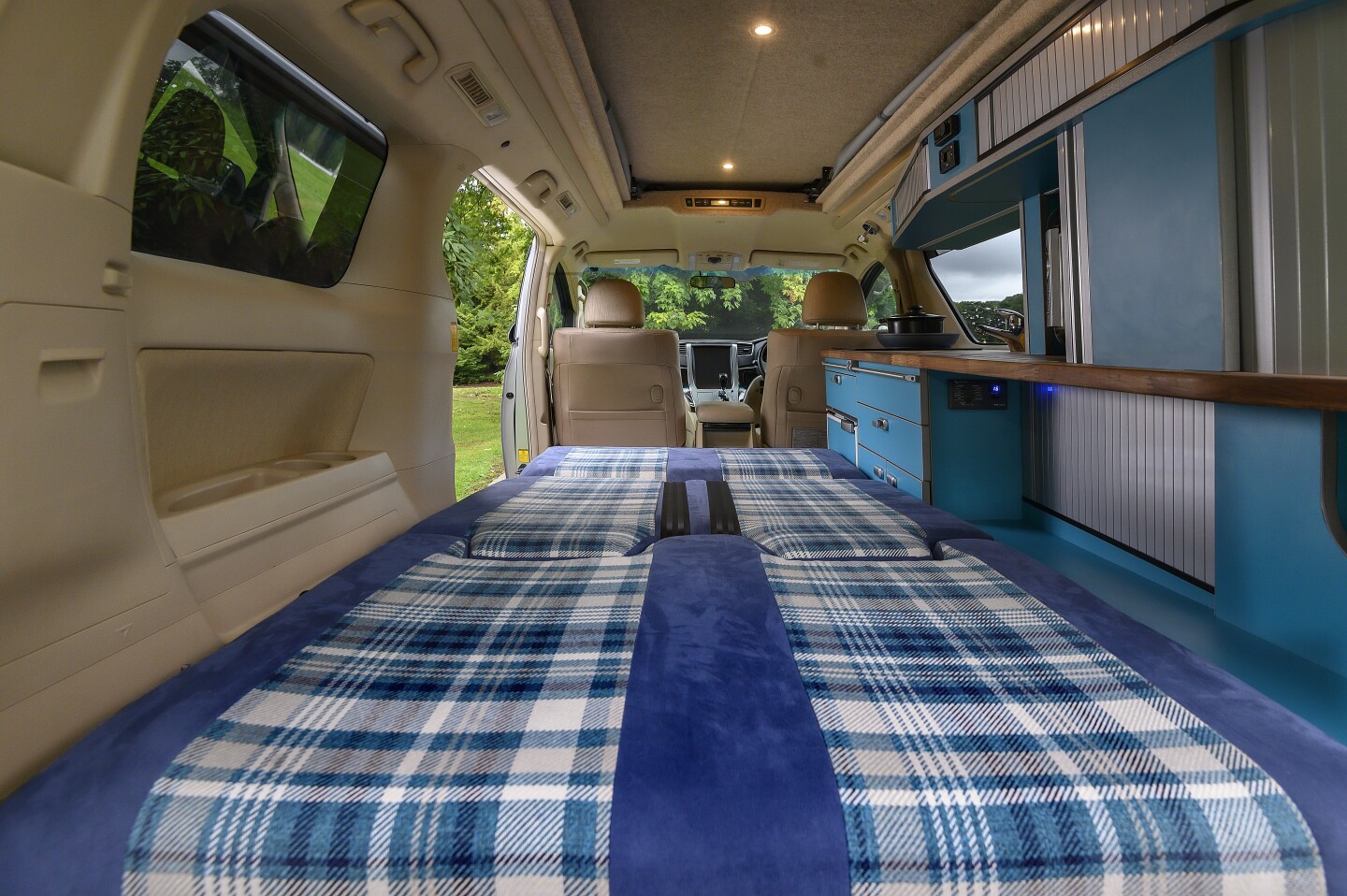 The Eco Pioneer II has a two-seat bench that folds into a double bed next to the kitchen and storage console, differing from the Eco Explorer, which has a three-seat bench/full-width bed and no kitchen block or storage cabinetry (portable kitchen components)