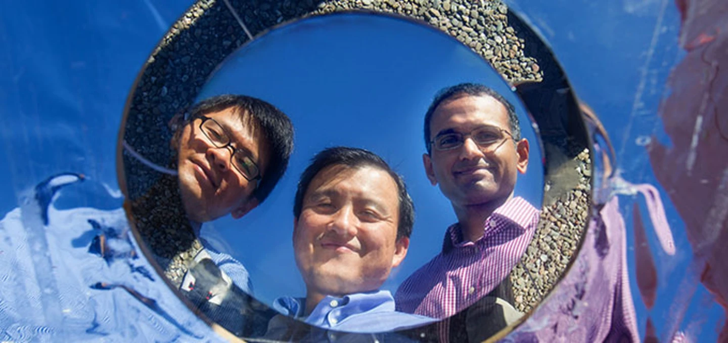 Stanford Professor Shanhui Fan, (center), gazes into the pizza- size prototype with co-authors Linxiao Zhu, (left), and Aaswath Raman, (right) (Photo: Norbert von der Groeben)