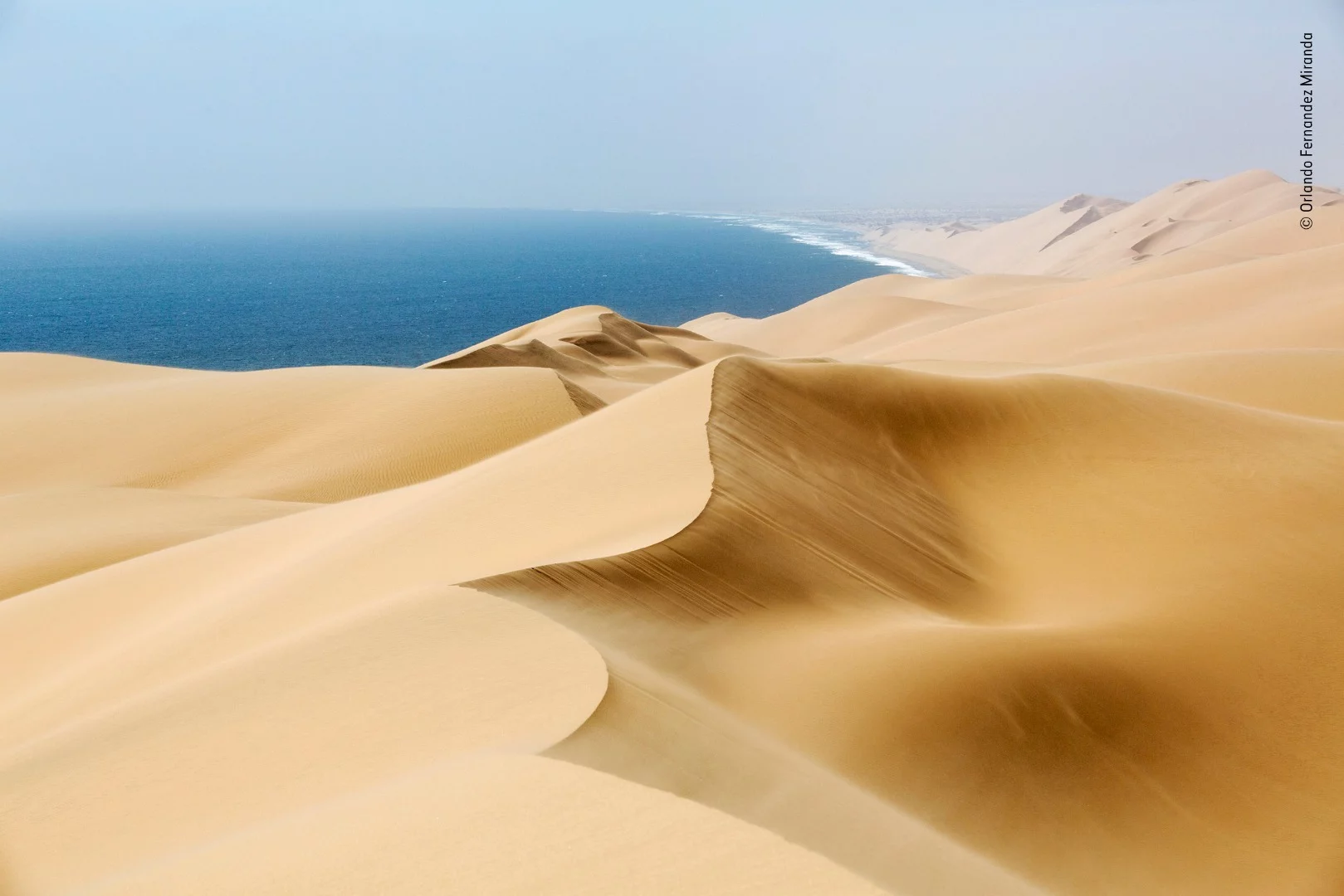 Windsweep by Orlando Fernandez Miranda, Spain. Winner 2018, Category: Earth’s Environments. Standing at the top of a high dune on Namibia’s desert coastline, where mounds of wind-sculpted sand merge with crashing Atlantic waves, Orlando faced a trio of weather elements: a fierce northeasterly wind, warm rays of afternoon sunshine and a dense ocean fog obscuring his view along the remote and desolate Skeleton Coast