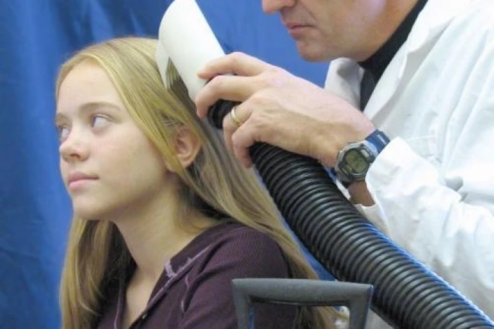 University of Utah biologist Dale Clayton demonstrates the the latest prototype of the LouseBuster on his daughter, Miriam. The new, chemical-free treatment kills almost all louse eggs and enough hatched lice to prevent them from reproducing, effectively