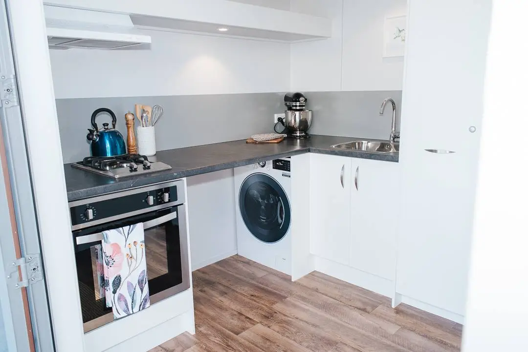 The Larissa and Tyler Tiny House kitchen, shown with the washing machine revealed