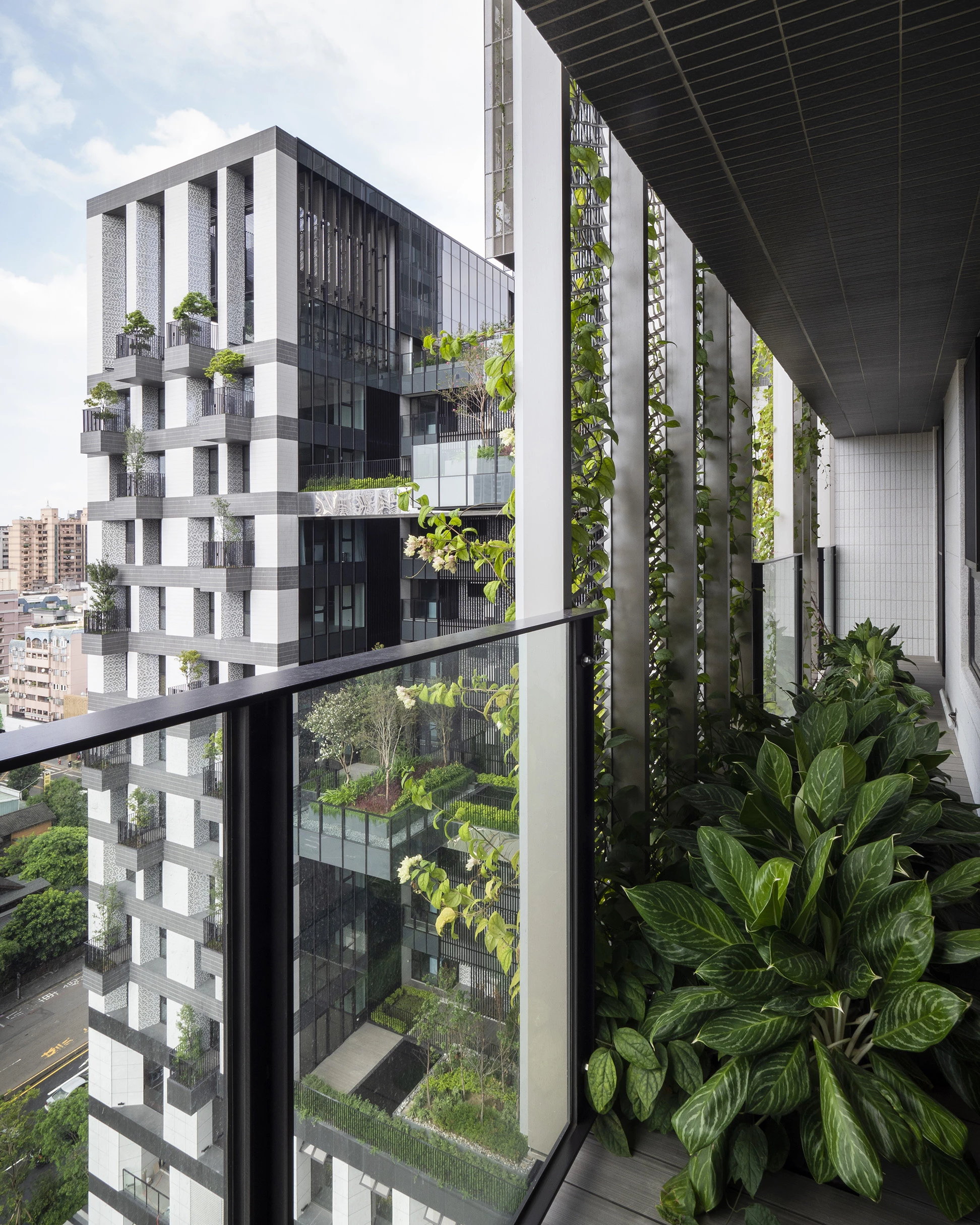 One of the Sky Green towers' facades features small balconies that are planted with trees, while the other has mesh screens that serve as trellis for creeper plants