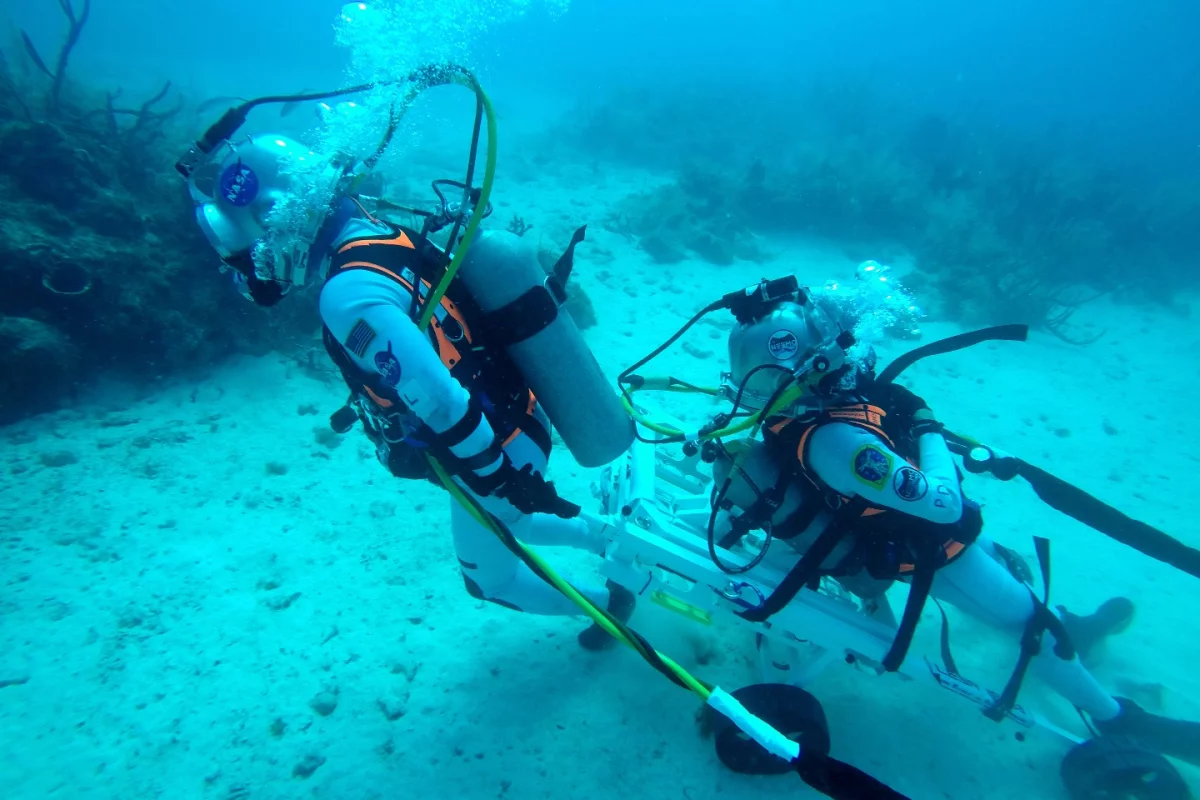 NASA astronaut Kjell Lindgren pulling Pedro Duque on a stretcher in a simulated lunar rescue