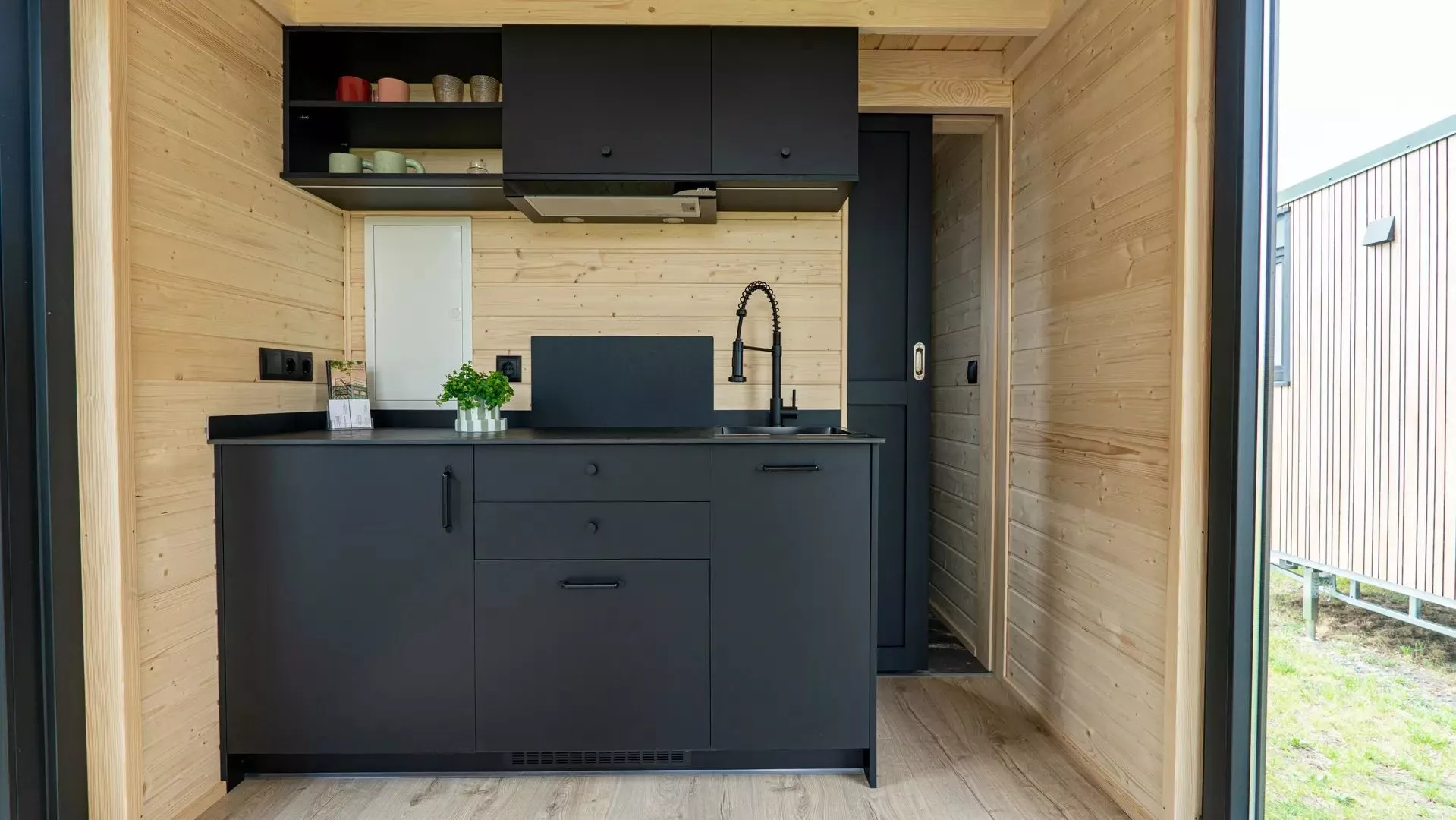 The compact kitchen is home to an induction cooktop with extraction hood, a small sink and upper and lower storage