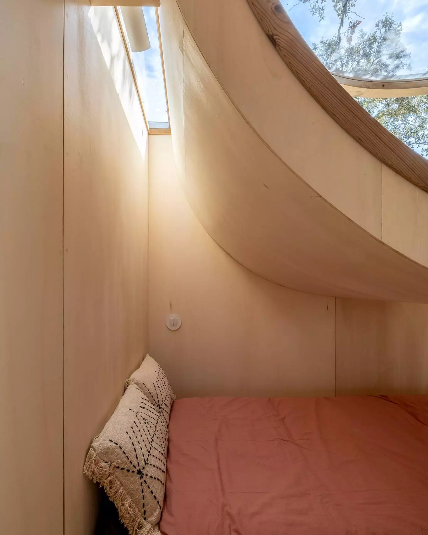 The Terra m1_Tiny House on Wheels' main bed is situated below the large porthole window