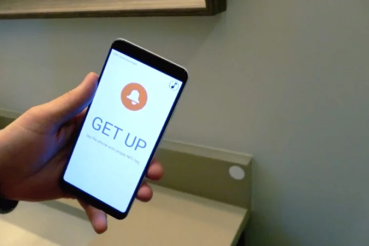 The EzLarm app works with an NFC tag (white disc to the right of the phone)
