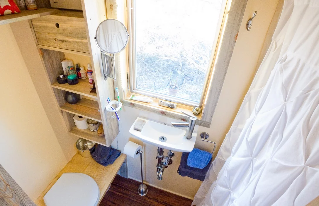 The bathroom has a small hand basin, shower cubicle and composting toilet