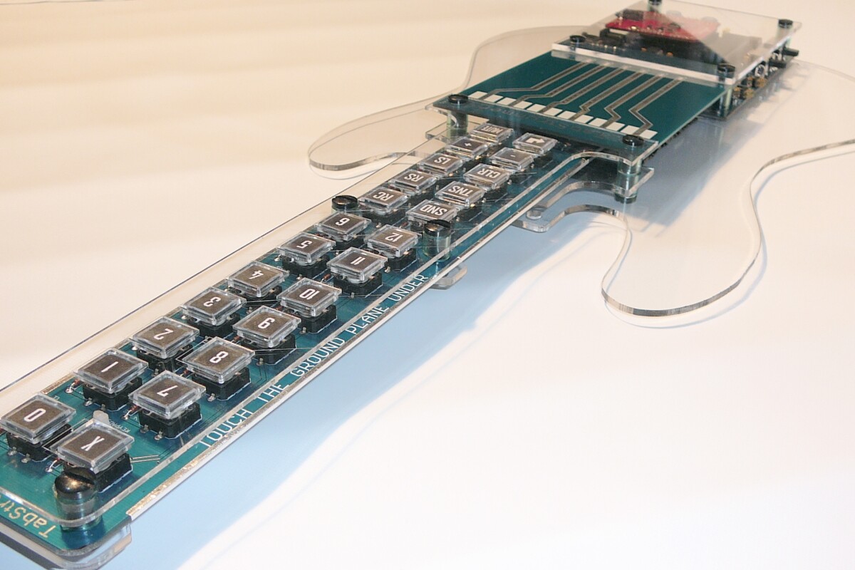 The guitar-shaped Tabstrummer programmable MIDI controller allows users to create and register guitar chords to buttons on the neck and strum songs via PCB strings