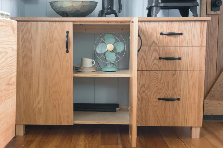 The interior includes a folding hardwood desk, a butler's cupboard and countertop, a sofa bed, bunk beds, shelving units, and a bookcase (Photo: Güte)