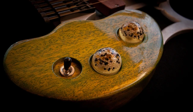 The guitar's volume and tone controls made from resin, and are joined by a 3-way pickup selector on the lower wooden element