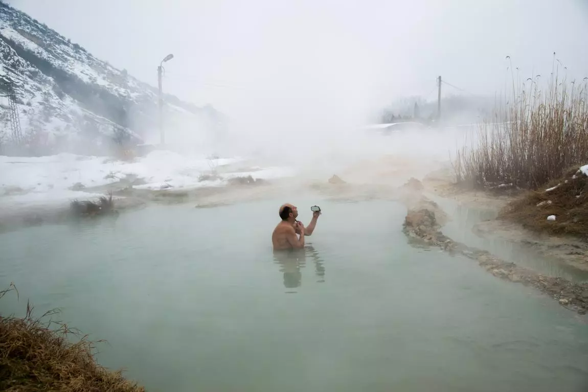 Urban Photo Awards. Remarkable Reward - People. Bulgaria. A man shaves himself in the middle of a hot mineral spring in winter, using a rear-view mirror from an old car
