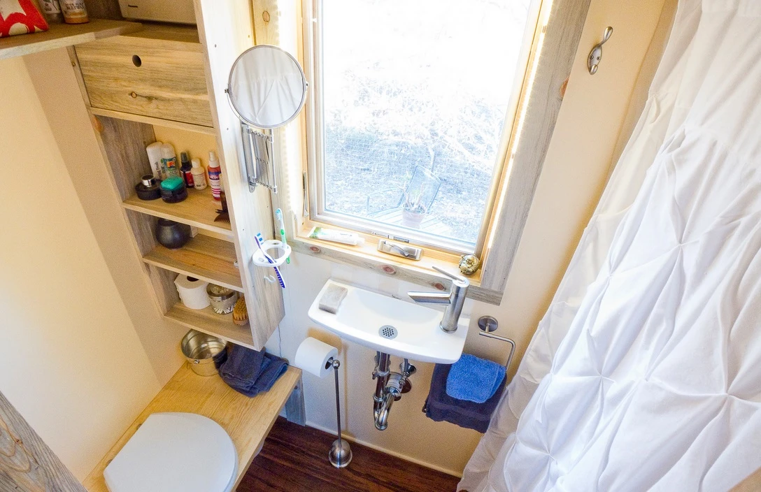 The bathroom has a small hand basin, shower cubicle and composting toilet