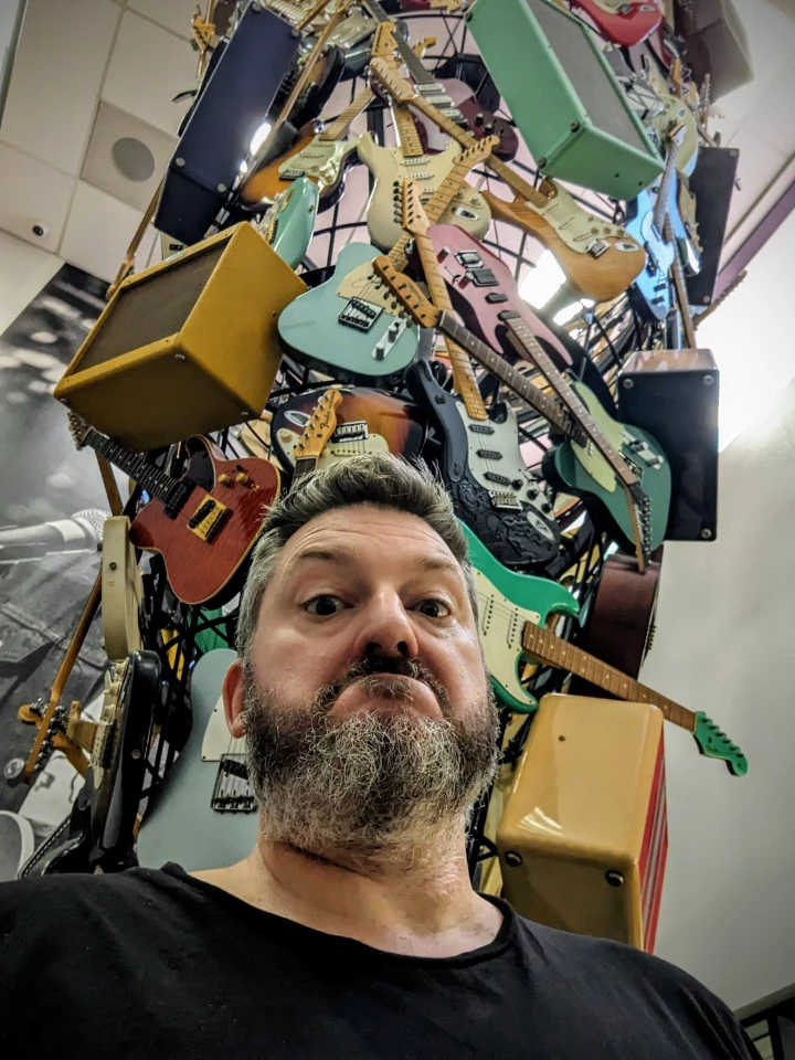 The author pops a selfie under the "tornado" of guitars and amps in the Fender office lobby