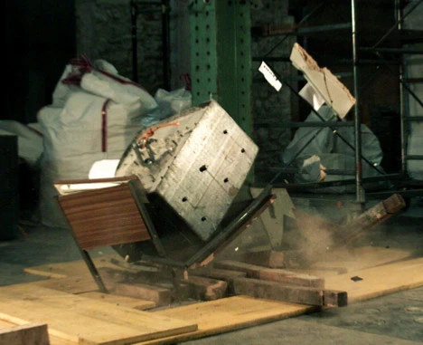 While it might block a few pieces of stray drywall and glass, a wooden desk isn't going to withstand the crushing weight from large chunks of concrete or steel