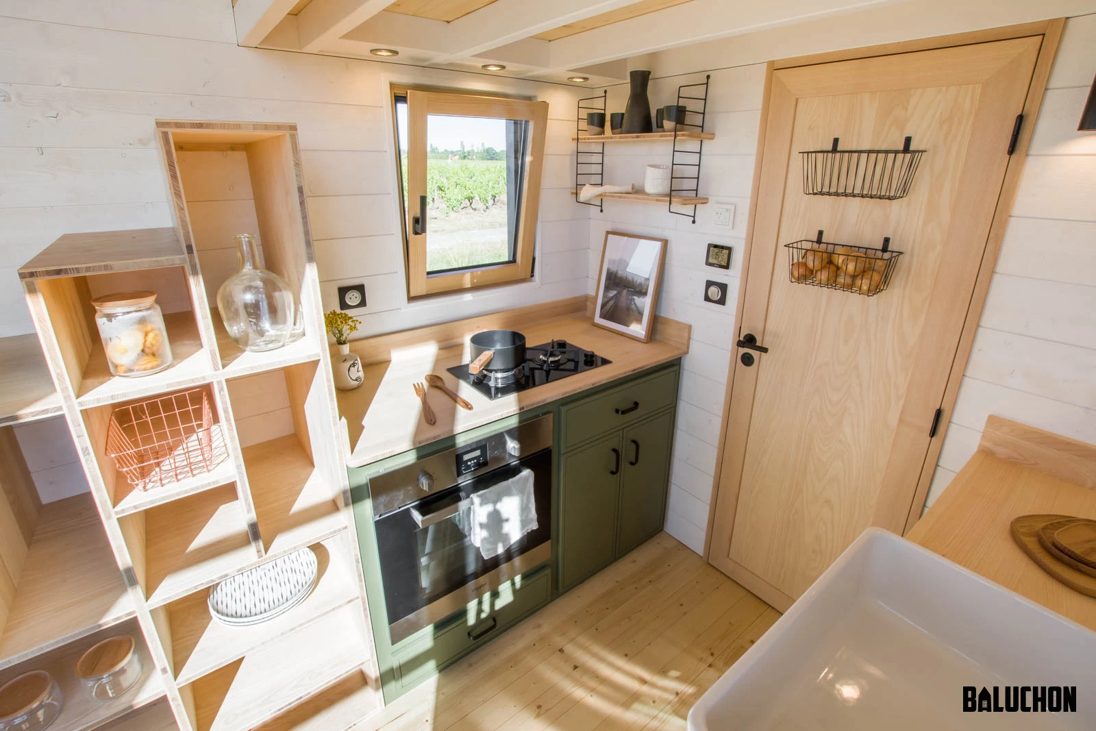 The Tiny House Sauvage's kitchen includes an oven and two-burner propane-powered stove